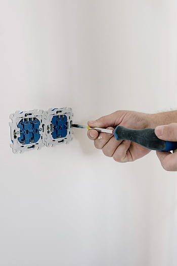 Close-up of hands using a screwdriver to install electrical sockets on a white wall. HD phone wallpaper