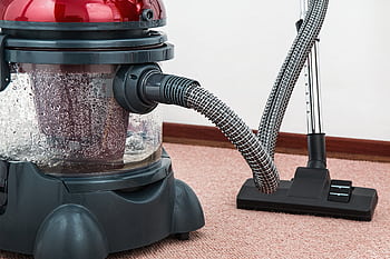 Close-up of a modern vacuum cleaner with water filtration on carpet floor indoors. HD wallpaper