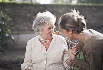 Joyful interaction between an elderly woman and her granddaughter in a sunny outdoor setting. HD wallpaper