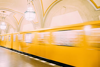 A vibrant yellow train speeds through a Berlin subway station, showcasing urban transportation. HD wallpaper