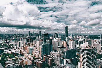 Dynamic cityscape featuring towering skyscrapers and a vibrant urban skyline under a cloudy sky. HD wallpaper