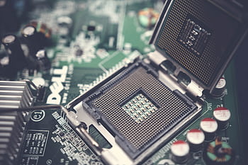 Detailed close-up shot of a computer motherboard featuring an open CPU socket and electronic components. HD wallpaper