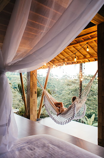 Woman lounging in hammock at tropical resort, enjoying serene view. HD phone wallpaper