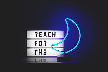 A neon crescent moon sign with a motivational quote in a dark setting. HD wallpaper