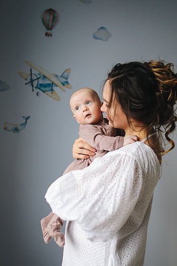 A mother lovingly holds her baby in a nursery decorated with airplanes. HD phone wallpaper