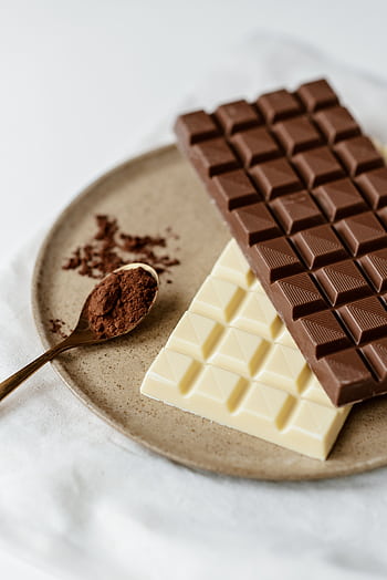A delicious assortment of milk and white chocolate bars with cocoa powder on a plate. Perfect for confectionery enthusiasts. HD phone wallpaper