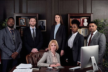 Diverse group of professionals in corporate attire posing confidently in an office environment. HD wallpaper