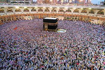 Aerial view of a large crowd of pilgrims gathered around the Kaaba in Mecca for religious rituals. HD wallpaper