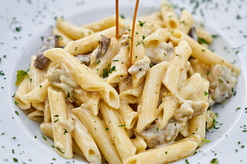 Close-up of creamy pasta with herbs, offering a delicious Italian meal. HD wallpaper