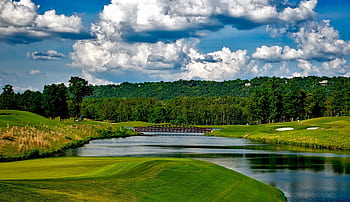 Scenic golf course with lush greenery, river, and a bridge under a bright summer sky. HD wallpaper