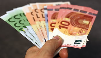 A fan of euro banknotes in various denominations held in a hand. HD wallpaper