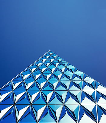 A striking of modern architecture with geometric glass panels reflecting a clear blue sky. HD phone wallpaper