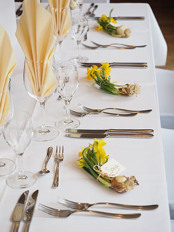 Sophisticated dining arrangement with daffodils and fine cutlery on a white tablecloth. HD phone wallpaper