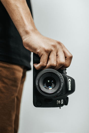 A close-up shot of a hand holding a DSLR camera, ideal for graphy concepts. HD phone wallpaper
