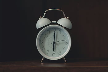 Close-up of a classic white vintage alarm clock on a wooden surface. HD wallpaper