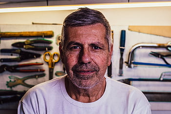 Portrait of a senior man with tools in the background, exuding confidence. HD wallpaper