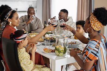 A joyful family gathering sharing a meal indoors, celebrating with wine and delicious food. HD wallpaper