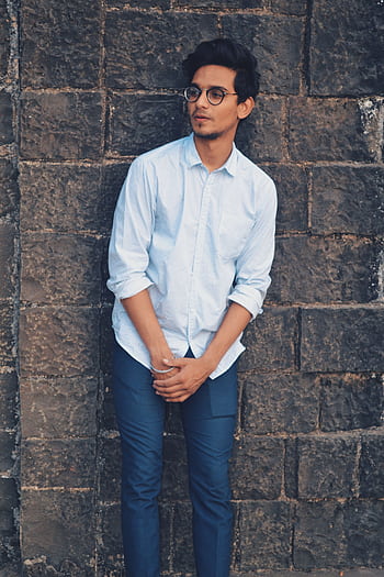 Stylish young man with eyeglasses posing against a brick wall outdoors. HD phone wallpaper