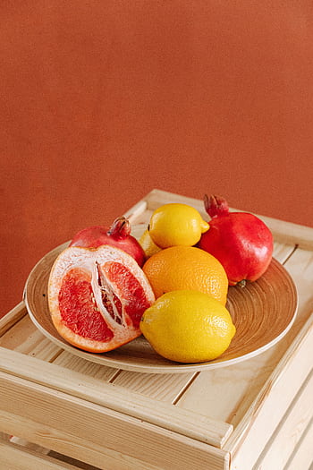 Colorful fruit arrangement with citrus and pomegranates on wooden crate. HD phone wallpaper