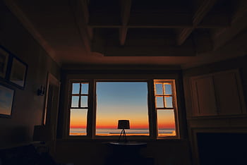 Dark silhouette of a room with a stunning sunset view through a window, creating an artistic interior design ambiance. HD wallpaper