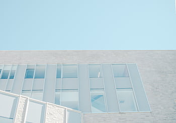 Low angle view of a modern glass facade against a bright blue sky in London, Ontario. HD wallpaper