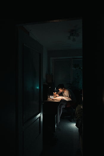 A young man studies intensely at his desk at night, illuminated by a desk lamp. HD phone wallpaper