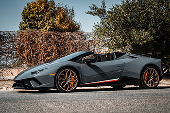 Luxury convertible sports car with orange accents parked outdoors on a sunny day. HD wallpaper