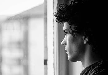 Profile portrait of a young man looking thoughtfully out of a window, in black and white. HD wallpaper