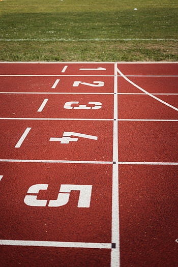 Close-up view of a red running track with numbered starting lanes, perfect for athletic themes. HD phone wallpaper