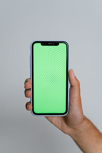 A close-up of a hand holding a smart with a vibrant green screen, ideal for mockups. HD phone wallpaper