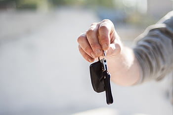 Close-up of a hand handing over car keys, signifying purchase or rental. HD wallpaper