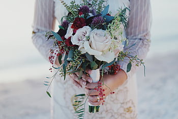 Close-up of a bride holding a beautiful bouquet at an outdoor wedding ceremony. HD wallpaper