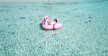 A woman enjoying leisure time on a flamingo float in the clear waters of Isla Mujeres. HD wallpaper