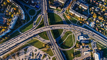 Aerial shot of a complex highway intersection in a vibrant urban cityscape. HD wallpaper