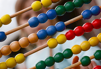 Close-up of colorful wooden abacus with a child learning math in the background, focusing on education and early childhood development. HD wallpaper