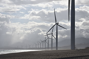 A row of wind turbines along a cloudy beach shoreline in Vigan City, Philippines. HD wallpaper