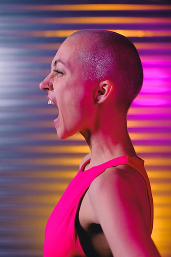 Bald woman in vibrant colors expressing strong emotion during studio shoot. HD phone wallpaper