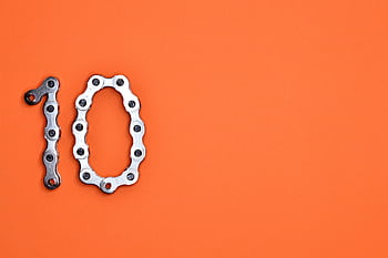 Bicycle chain arranged to form the number ten against a bright orange background. HD wallpaper