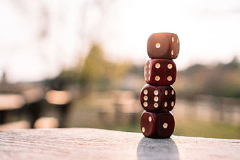 Five red dice stacked in sunlight on an outdoor table, creating a playful yet strategic scene. HD wallpaper