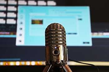 Close-up of a micro with a blurred computer screen in the background, ideal for podcast themes. HD wallpaper