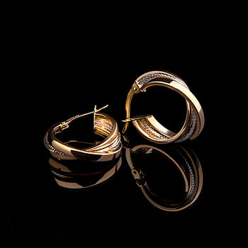 Close-up of luxurious gold earrings reflecting on a glossy black surface, showcasing elegant design. HD phone wallpaper