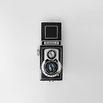 Top-view of a classic Reflecta II twin-lens reflex camera on a white background. HD phone wallpaper