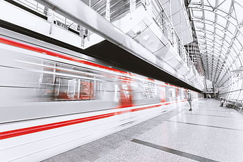 Blurred high-speed train in a sleek modern station, capturing urban commuting and motion. HD wallpaper