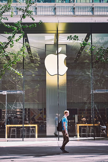 A casual scene of a man walking past the iconic glass facade of an Apple Store in Beijing, China. HD phone wallpaper
