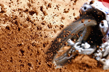 Close-up of a motocross bike kicking up dirt during an offroad race. HD wallpaper