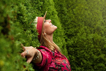 A joyful woman enjoying nature, embracing dom in a lush green park. HD wallpaper