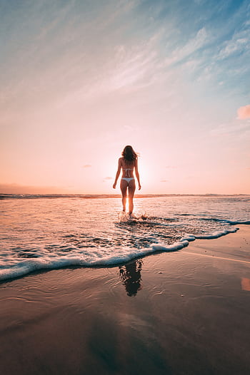 A woman stands in the ocean at sunset on Encinitas Beach, California, creating a serene summer scene. HD phone wallpaper