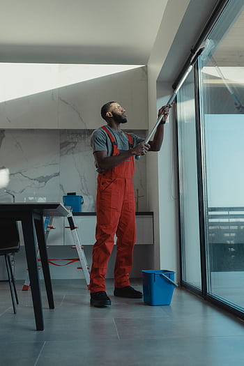 A man in coveralls cleans a large window in a stylish, modern home interior. HD phone wallpaper