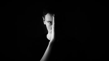 Moody black and white portrait of a man in a studio setting with high contrast lighting. HD wallpaper