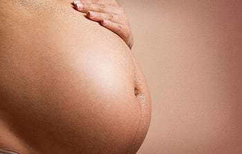 An intimate close-up of a pregnant woman's abdomen, highlighting maternity and parenthood. HD wallpaper